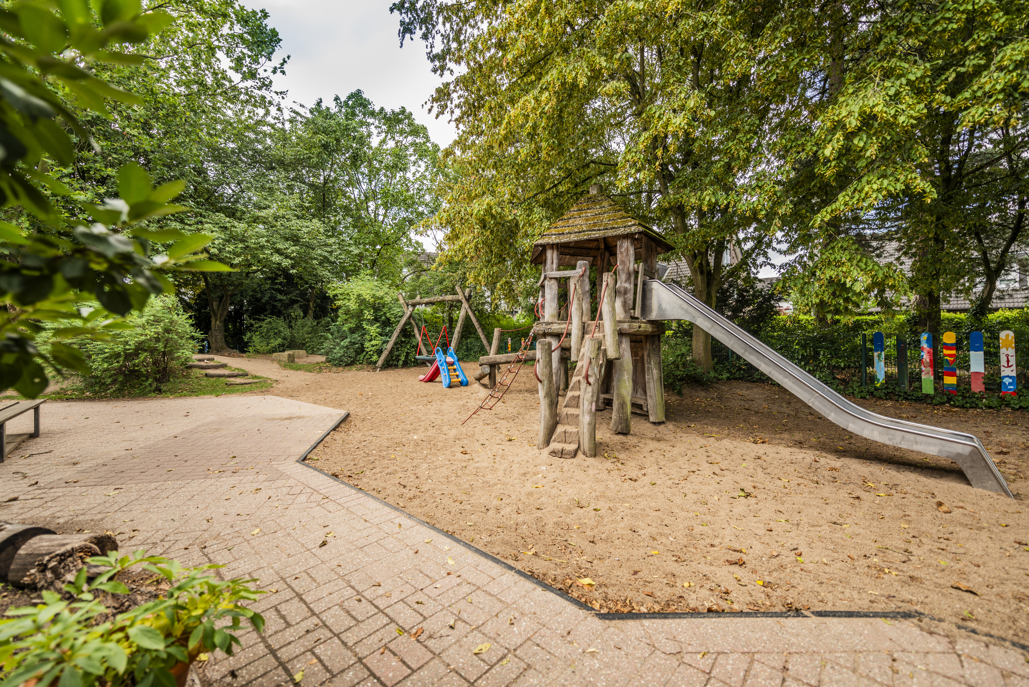 Abgebildet ist unser Kletterturm mit Rutsche  und im Hintergrund ist eine Nestschaukel zu erkennen.